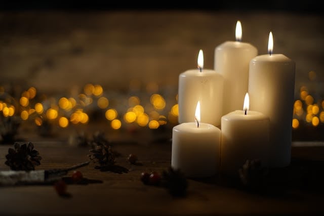 Five white pillar candles glow softly against a warm, twinkling background, creating a peaceful tribute with direct cremation in Columbus, OH