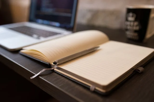 An open notebook beside a laptop and coffee mug creates a calm, reflective scene for cremation services Columbus, OH