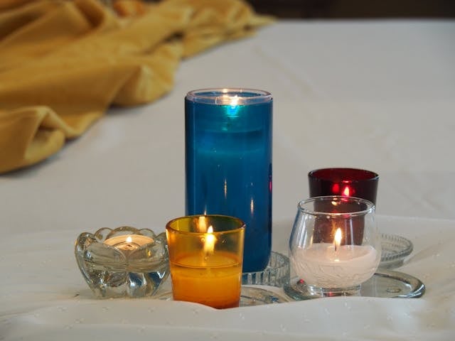 Colored candles arranged on a white cloth create a calm and comforting scene for cremation services Columbus, OH